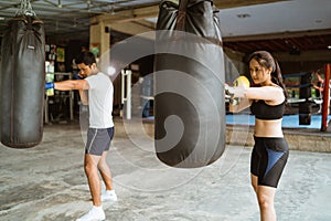 the male and female boxer hitting the sand bag