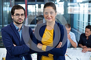 Male and female business executive standing with arms crossed