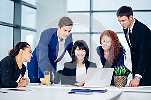 Male and female business people around laptop computer in office