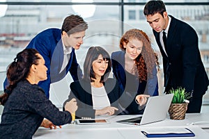 Male and female business people around laptop computer in office