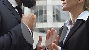 Male and female colleagues disputing and gesturing hands outdoor, conflict