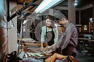 Male and female craftsmen in aprons working with leather
