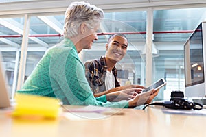 Male and female designers discussing over digital tablet at desk