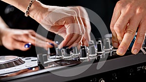 Male and female DJ hands on a DJ consolle