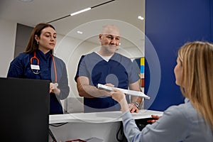 Male and female doctors checking schedule near reception desk