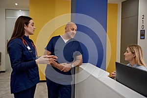 Male and female doctors checking schedule near reception desk
