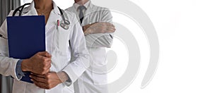 Male and female doctors with reports standing against white background