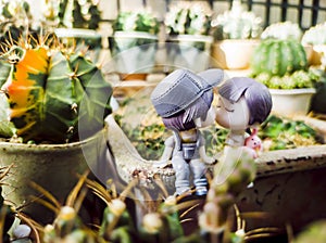 Male and female dolls sitting in the cactus garden.