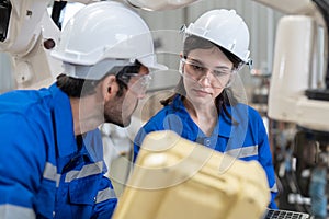 Male and female engineer training using remote controller control robot arm welding machine in industrial factory