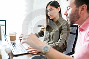 Male And Female Executives Discussing Over Laptop At Desk