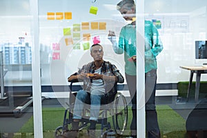 Male and female executives discussing over sticky notes in office