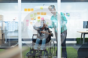 Male and female executives discussing over sticky notes in office