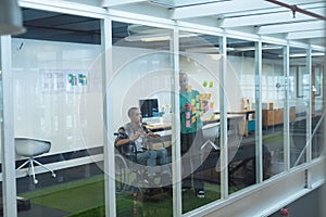 Male and female executives discussing over sticky notes in office