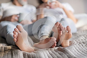 Male and female feet barefoot on bed