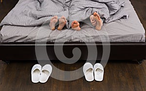 Male and female feet, man`s hand scratching his feet under grey