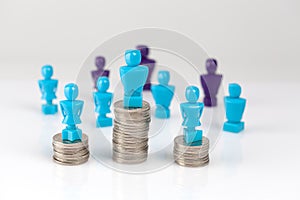 Male and female figurines standing on top of coin piles with other figurines in the background.