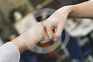 Male and female fists bumping in office, close up