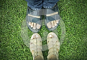 Male and female foots on green grass. photo