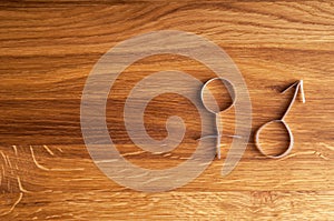 Male and female gender symbols on wooden background with copy space.