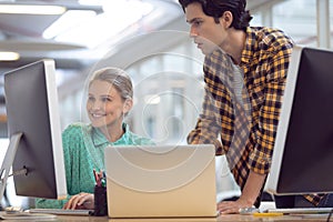 Male and female graphic designer discussing over computer