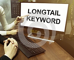 Male and female hand, computer with text Longtail Keyword with office background