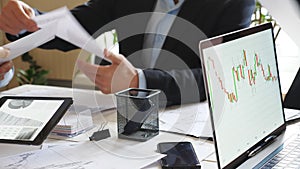 Male and female hands of business team analyzing financial reports at the desk. Arms of business people examining graphs