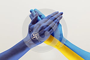 Male and female hands colored in flags of Ukraine and NATO photo