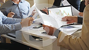 Male and female hands of coworkers examining graphs in office. Business team sitting at the table and checking documents