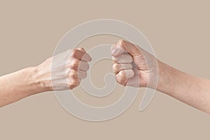 Male and female hands fist bump isolated on beige.