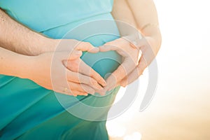 Male and female hands hold a pregnant belly closeup and copy space. Pregnant in a dress