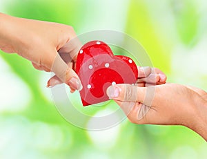 Male and female hands holding red heart