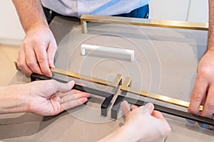 Male and female hands placing kitchen cabinet handles in configuration to make a selection for their home interior decor