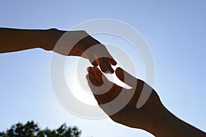 Male and female hands reaching out to each other outdoors