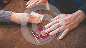 Male and female hands on table exchange Italian passport and money