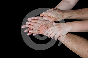 Male and female hands together on black background, old skin with wrinkles and veins, concept of health, age-related changes, love