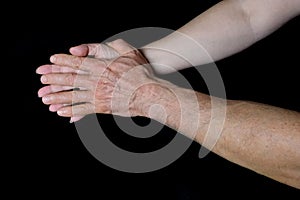 Male and female hands together on black background, old skin with wrinkles and veins, concept of health, age-related changes, love