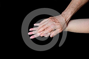 Male and female hands together on black background, old skin with wrinkles and veins, concept of health, age-related changes, love