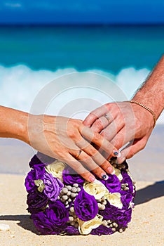 Male and female hands with wedding rings wedding bouquet lying o