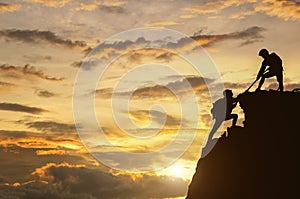 Male and female hikers climbing up mountain cliff and one of the