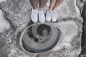 Male and female legs shod in white comfortable sports shoe