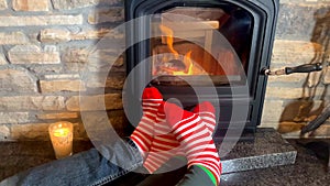 Male and female legs in striped socks dancing together near the hot fire of a burning fireplace, Christmas