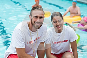 Male and female lifeguards crouching at poolside