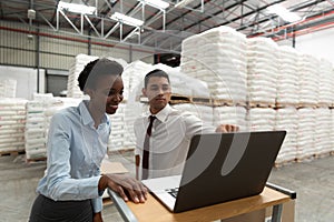 Male and female manager discussing over laptop at desk in warehouse