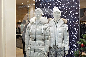 Male and female mannequins in stylish winter white clothes in a New Year`s shop window