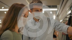 Male and female in masks visiting modern store during pandemic