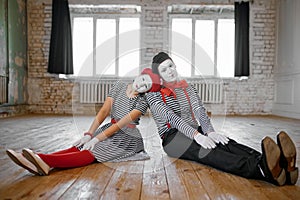 Male and female mime artists sitting on the floor