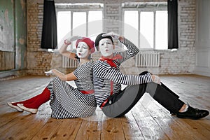 Male and female mime artists sitting on the floor