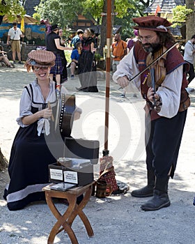 Male and female musicians in costumes perform on ancient instruments at a Renaissance Faire