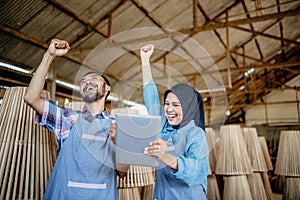 Male and female Muslim entrepreneurs looking at tablets with a victory expression