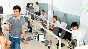 Male and female office co-workers having conversation at desk in office